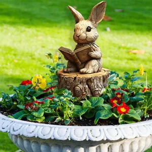 Detail of garden bunny sculpture reading a book placed in a flower pot with greenery