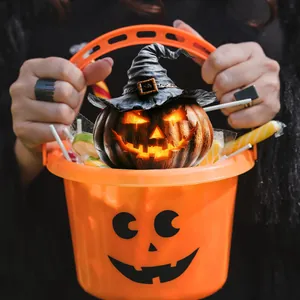 Glow Jack-o'-lantern with witch hat in a plastic trick or treat bucket with candies