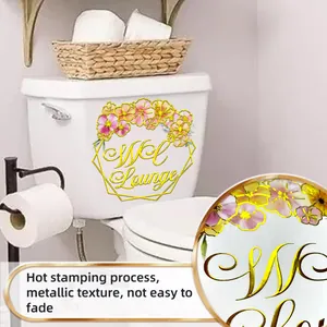 Λεπτομέρεια floral αυτοκόλλητου με χρυσά γράμματα σε καζανάκι τουαλέτας στο μπάνιο