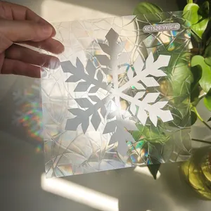 Close-up of snowflake window film showing vibrant rainbow refraction under sunlight