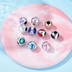 Silver and gold alloy spacer beads with colorful crystal stones on pink marble stand