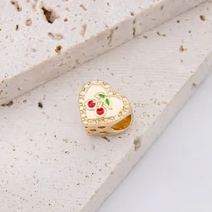 Gouden hartvormige bedel met rood kersen-emaille op een natuurstenen ondergrond