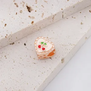 Detail van een roségouden hartbedel met rode kers op een witte stenen voetstuk