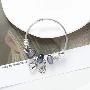 Silver twisted cable bracelet with heart charms and floral beads on white tray