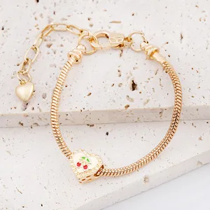 Gouden slangenarmband met rode kersenhart hanger op witte marmeren ondergrond