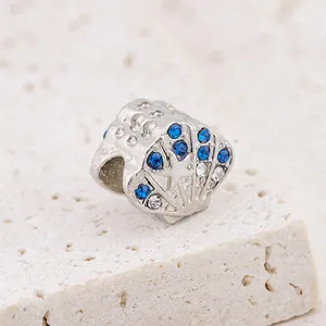 Macro view of shell-shaped bead with starfish detail and blue rhinestones for DIY bracelet