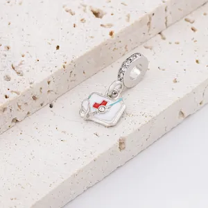 Silver medical charm with stethoscope and red cross on a stone background