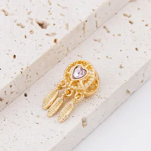 Macro detail of a golden dreamcatcher bead with pink heart crystal and three feathers