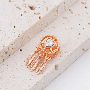 Macro view of rose gold dreamcatcher charm with heart cubic zirconia and three feathers