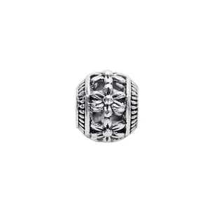 Macro view of silver hollow charm bead featuring vintage embossed floral pattern detailing