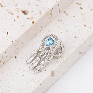 Detailed close-up of a dreamcatcher charm with blue heart stone and three feathers