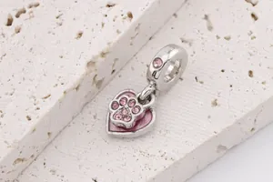 Macro shot of silver-toned pink enamel heart and paw print charm with cubic zirconia