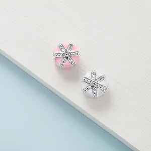 Elegant pink and white enamel charms with silver cross patterns and sparkling accents