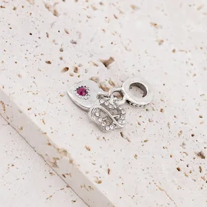 Silver double heart charm with pink stone and zircon inlay on stone surface
