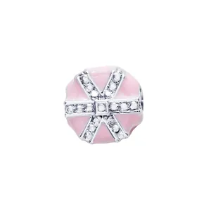 Macro view of a round pink enamel charm with silver crisscross crystal bands for DIY bracelets