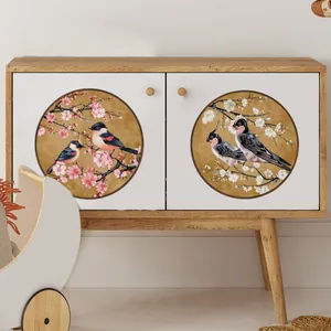 Détail de stickers oiseaux et fleurs sur un meuble en bois aux poignées rondes