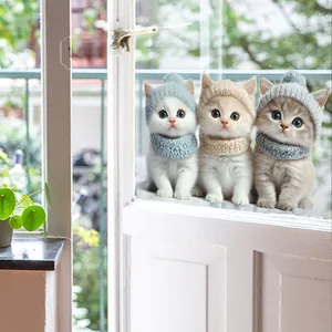 Drei 3D-Cartoon-Katzen mit Strickmützen und Schals Aufkleber auf einem Glasfenster