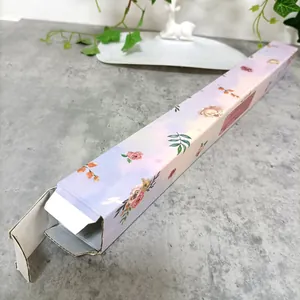 Detalle de caja de regalo larga floral con degradado púrpura sobre mármol elegante