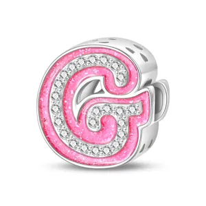 Macro detail of pink glitter letter G charm with zircon pavé and hollow hearts