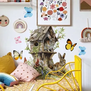 Détail de stickers muraux maison de lapin et papillons colorés sur un mur blanc de chambre