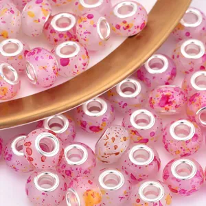 Macro detail of pink resin beads with splash ink patterns and silver metal core