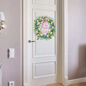 Détail d'autocollant de Pâques avec couronne florale et œufs colorés sur une porte blanche
