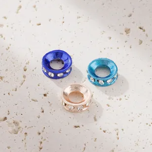 Drei kristallbesetzte Abstandsperlen aus Legierung in Blau und Roségold auf Marmor