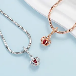 Silver and rose gold crown charm bracelets with red heart stones on blue background