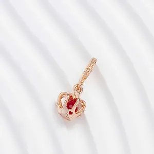 Rose gold crown charm with a red stone and heart cutouts on a textured backdrop