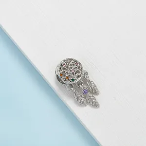Silver dreamcatcher charm with tree of life design and colorful crystals on wood