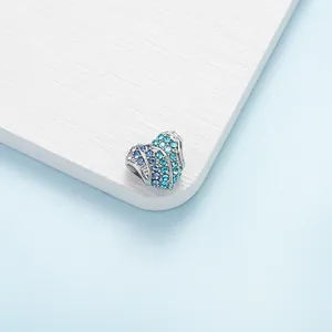 Détail macro du charm en forme de cœur avec pierres de zircon bleu dégradé sur argent