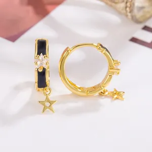 Macro view of gold star hoop earrings with black enamel inlay and zircon stone detail