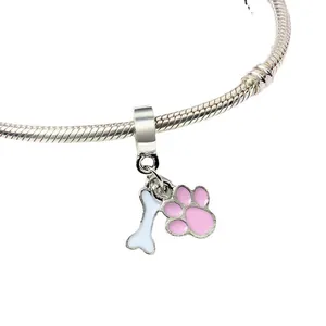 Detail of silver charm bracelet with pink enamel paw print and white bone pendants