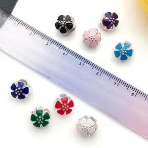 Colorful enamel flower charms for DIY jewelry making with ruler scale for size reference