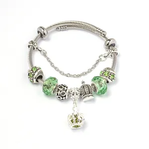 Zilveren slangenarmband met gefacetteerde groene glaskralen en kroonbedeltjes