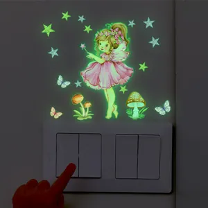 Close-up of luminous fairy and stars stickers glowing green on wall next to light switch