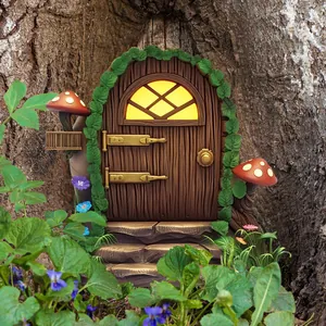 Close-up of a miniature fairy garden door with glowing window and mushrooms on a tree