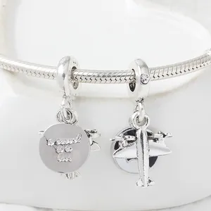 Silver airplane charm bracelet with To Travel Is To Live engraved disc on white tray