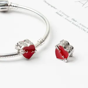 Detail of red enamel heart charms and arrow motif on a silver snake chain bracelet