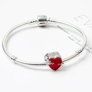 Detail of silver snake chain bracelet featuring a vibrant red enamel heart charm and clasp