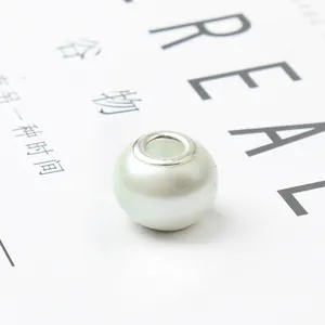 Macro shot of white glass charm bead with silver core on minimalist magazine background