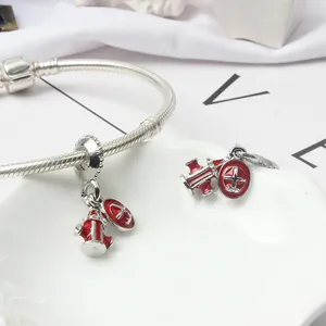 Silver bracelet with red enamel fire hydrant and shield charms on a shell tray