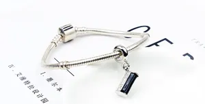 Macro shot of silver snake chain bracelet with black enamel and zircon pavé charm