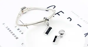 Close-up of silver snake chain bracelet with black and white crystal purse pendants