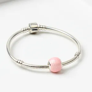Detalle de pulsera de cadena de serpiente plateada con cuenta rosa texturizada y cierre