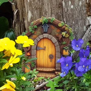 Detail of a resin fairy garden door with yellow wood texture among real flowers