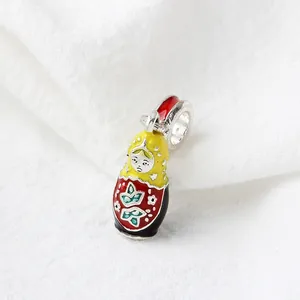 Macro shot of colorful enamel Russian doll charm with yellow and red flower details