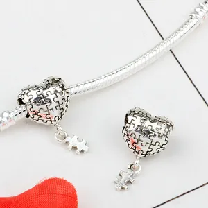 Détail des breloques cœur puzzle sur un bracelet chaîne serpent argenté au fini antique