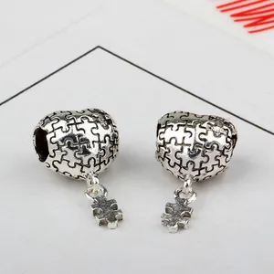 Détail du charm cœur puzzle en argent poli avec un élément de puzzle mobile suspendu