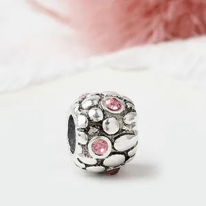 Macro view of vintage silver charm with pink zircon stones and pebble texture design